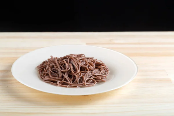 White plate with soba noodle on a light wooden table. — Stock Photo, Image