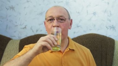 Bir adam bardaktan hafif köpüklü bira içer..