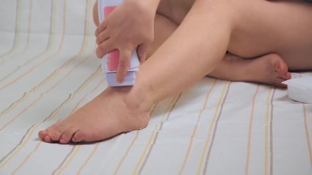 Een vrouw thuis maakt ontharing, brengt cartridge hete was aan op de huid van haar benen. — Stockvideo