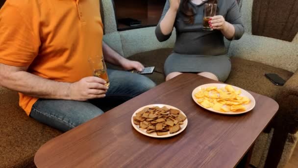 Σύζυγος και γυναίκα στο σπίτι στον καναπέ μαλώνουν για την τηλεόραση τι να δουν και να πιουν μπύρα χωρίς πρόσωπα — Αρχείο Βίντεο