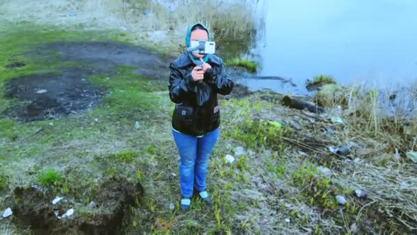 Une femme au bord de la rivière contrôle un quadrocopter depuis un smartphone . — Video