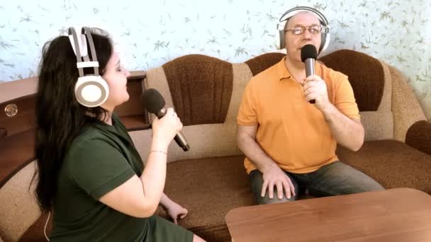 Παντρεμένο ζευγάρι στο σπίτι με ακουστικά τραγουδώντας σε μικρόφωνο — Αρχείο Βίντεο