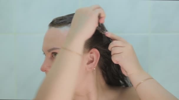 Una morena se tiñe el pelo con un cepillo — Vídeos de Stock