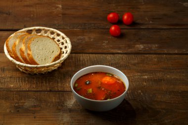 Tahta bir masada patates ve mantarlı bir tabak İtalyan domates çorbası ve ekmek..