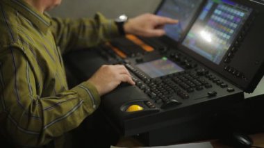 Konsoldaki bir erkek ışıklandırma yönetmeni şov için sahne ışığını programlıyor.