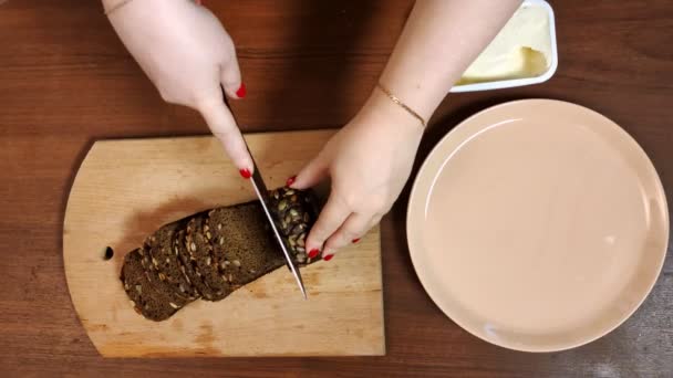 Tagli di mano femminili con un coltello su una tavola di legno segale hlnb con crusca . — Video Stock