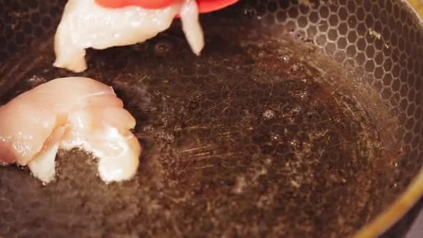 Щипці для м'яса поміщають на сковороду з попередньо розігрітими шматочками масла курки — стокове відео