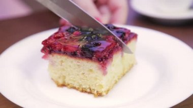 Bir kadın eli beyaz bir tabakta bıçakla pasta keser..