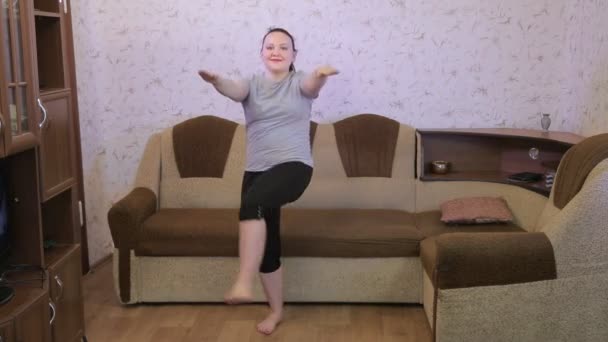 Eine junge Frau im Wohnzimmer beim Workout macht Beinschwünge nach vorne. — Stockvideo