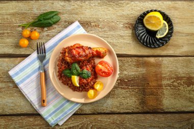 Tavuk budu, domates soslu kırmızı pilav, ahşap bir masa ve keten peçete..