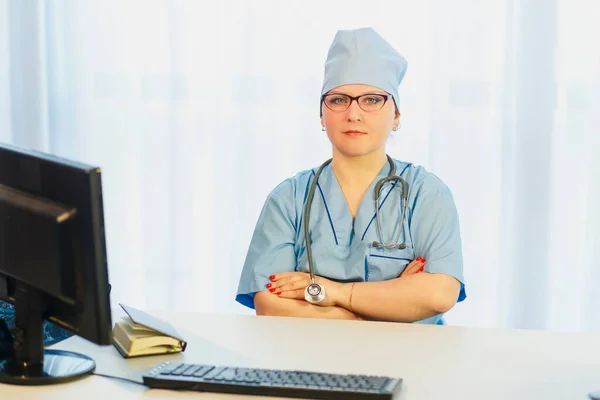 Женщина-врач сидит за столом со стетоскопом поверх костюма . — стоковое фото