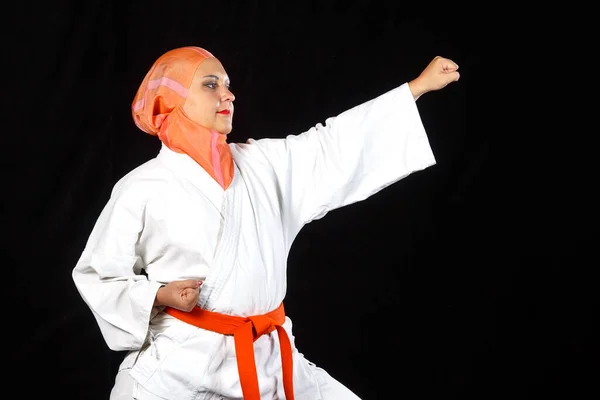 Young muslim woman in kimono and shawl during karate training over black background. — Stock Photo, Image