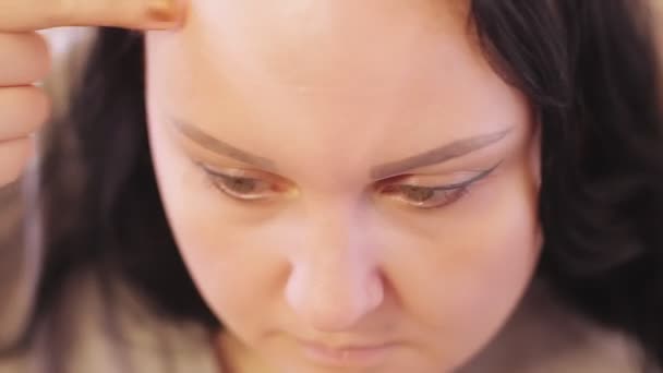 Una giovane donna si mette sul viso le fondamenta tonali di una casa davanti a uno specchio. Primo piano — Video Stock