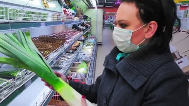 Γυναίκα αγοραστής σε μια προστατευτική μάσκα σε ένα κατάστημα επιλέγει λαχανικά κατά τη διάρκεια της περιόδου καραντίνας. Αργή κίνηση. — Αρχείο Βίντεο