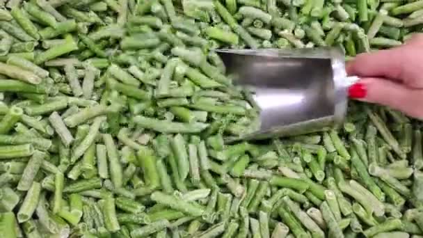 A female hand picks frozen vegetables in a store with a measuring spatula. Slow motion. Close up — Stock Video