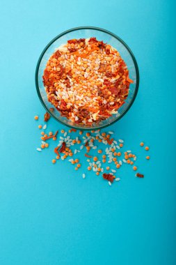 Mavi arka planda sarı mercimek bulunan cam kavanoz..