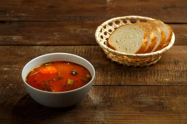 Een bord Italiaanse tomatensoep met aardappelen en champignons op een houten tafel en brood. — Stockfoto