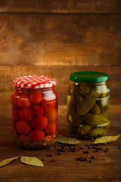 Frascos de pepinillos de tomates cherry encurtidos caseros en escabeche sobre una mesa de madera. Vertical —  Fotos de Stock