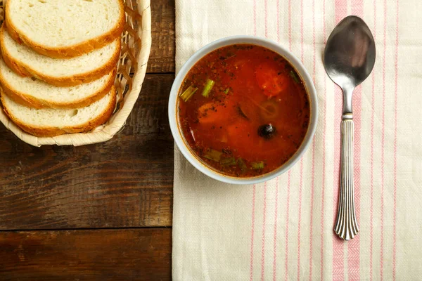 Легкая чашка итальянского томатного супа с картошкой и грибами на деревянном столе на салфетке и ложке с хлебом . — стоковое фото
