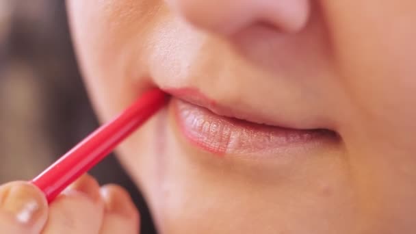 Молодая женщина наносит контурный карандаш на губы перед зеркалом — стоковое видео