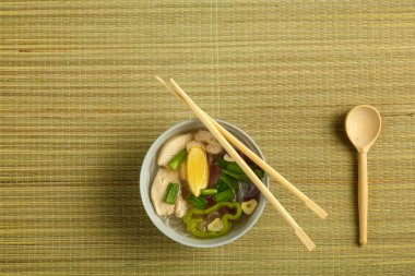 Hafif bir tabak Vietnamlı Pho çorbası. Paspaslı tavuk, çubuk ve kaşık..