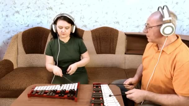 Ένας άντρας και μια γυναίκα στο σπίτι παίζουν μεταλικά με ακουστικά.. — Αρχείο Βίντεο