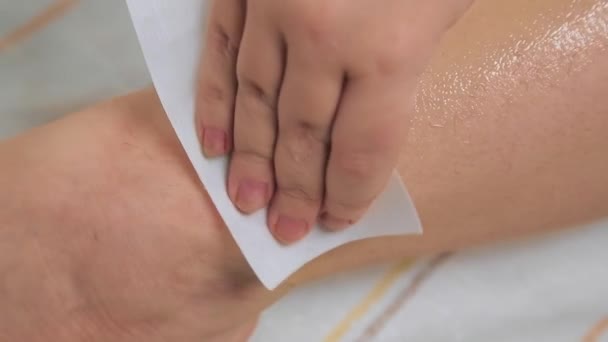 Una donna a casa fa depilazione rimuove la cera dalla pelle delle gambe con un tovagliolo speciale . — Video Stock