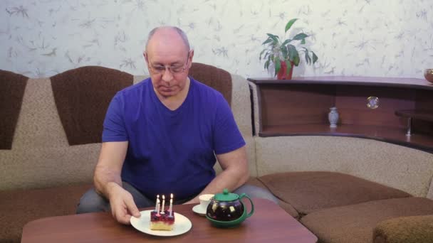 Egy szomorú ember egyedül ünnepli a születésnapját a karanténban, a koronavírus elfújja a gyertyákat a tortán.. — Stock videók