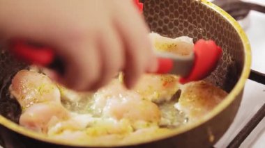 Et maşası tavada kızarmış tavuğu ters çevirir.