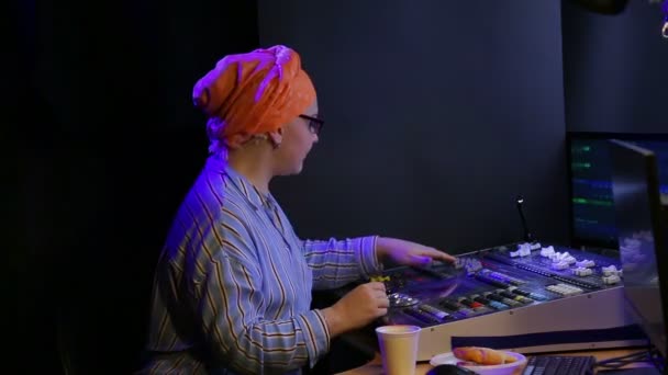 Donna ebrea in un foulard lighting designer programma la luce per lo spettacolo, mangiare fast food — Video Stock