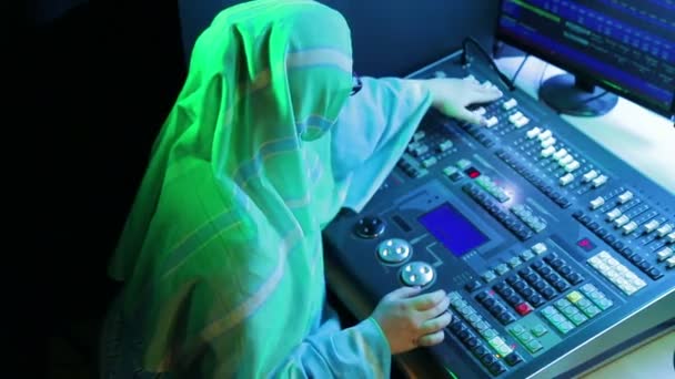 Μουσουλμάνα γυναίκα με γυαλιά, σχεδιάστρια φωτισμού προγραμματίζει το φως για μια παράσταση. — Αρχείο Βίντεο