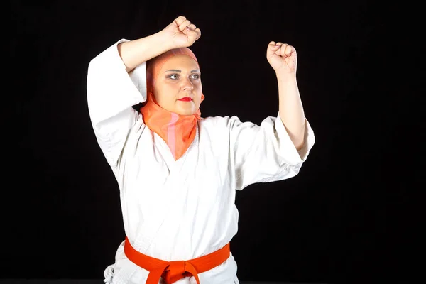 Ung muslimsk kvinna i kimono och hijab i träning på karaten svart bakgrund. Fotografering närbild. — Stockfoto