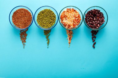 Mısır gevreği taneli cam kavanozlar, mercimek, fasulye, arkaplanda kahverengi pirinç ve serpiştirilmiş inlemeler..