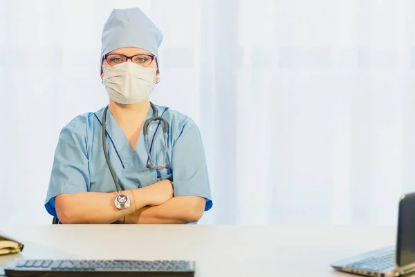 Een vrouwelijke arts zit aan een tafel met een stethoscoop bovenop een pak.. — Stockfoto
