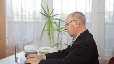 Ofiste çalışan, telefonu ve bilgisayarı olan bir adam..