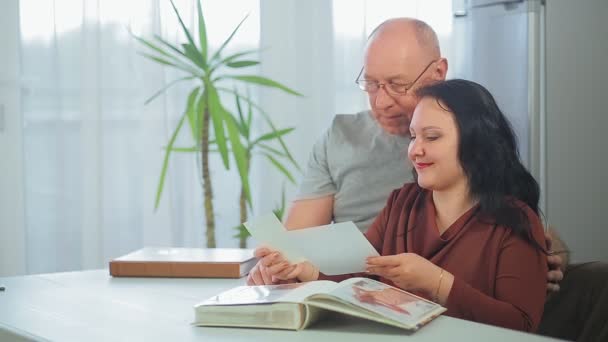 Una pareja casada marido y mujer en casa está considerando un álbum con fotos — Vídeos de Stock