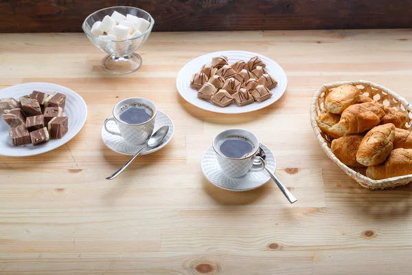 Две чашки кофе на деревянном столе с круассанами и сахаром . — стоковое фото