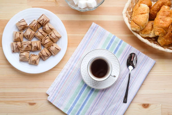 Чашка кофе на салфетках на деревянном столе с круассанами и вафлями . — стоковое фото