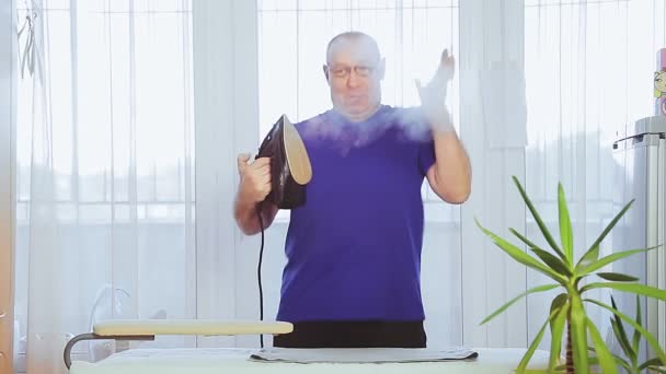 A man in the living room ironing clothes on an ironing board — Stock Video