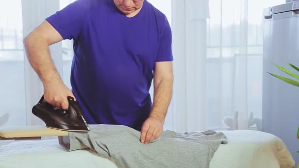 Ένας άντρας σιδερώνει ρούχα σε μια σιδερώστρα.. — Αρχείο Βίντεο