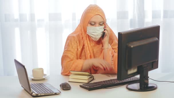 Eine Muslimin in einer Hijdaba in einem Büro arbeitet mit Informationen auf einem Computer — Stockvideo