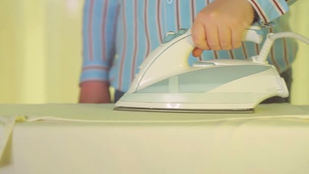 Strijkijzer in een vrouwelijke hand gladstrijkt wit linnen op een strijkplank — Stockvideo