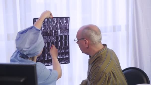 Een vrouwelijke arts adviseert een mannelijke patiënt over de resultaten van magnetische resonantie beeldvorming van de wervelkolom — Stockvideo