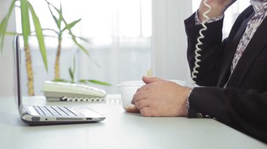 Bir erkek ofis çalışanı Çin eriştesiyle çalışırken bir şeyler atıştırıyor.