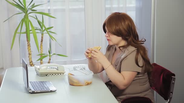 Kvinna på jobbet på kontoret vid lunchtid äter lunch paj. — Stockvideo