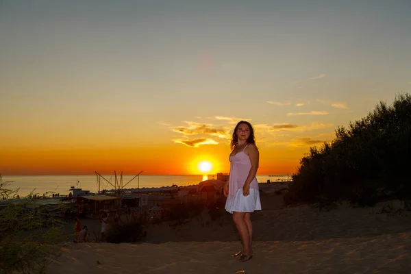 Femme en robe blanche sur fond de mer au coucher du soleil. — Photo