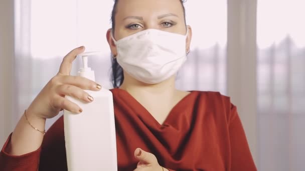 A woman in a public place in a protective mask disinfects her hands with a professional antiseptic — Stock Video