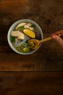 Hafif bir tabak Vietnam Pho çorbası ve ahşap bir masada tavuk..