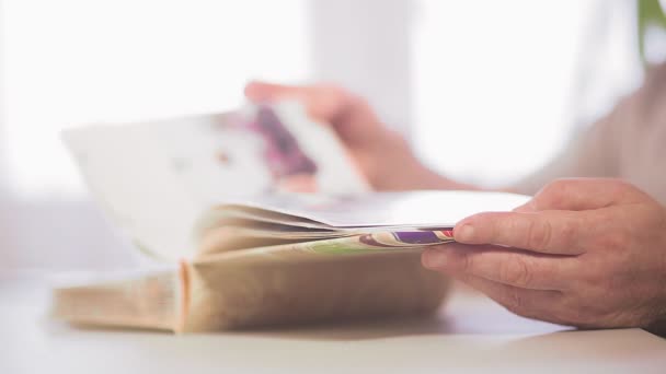 Mens hands flip through a large album with family photos. — Stock Video