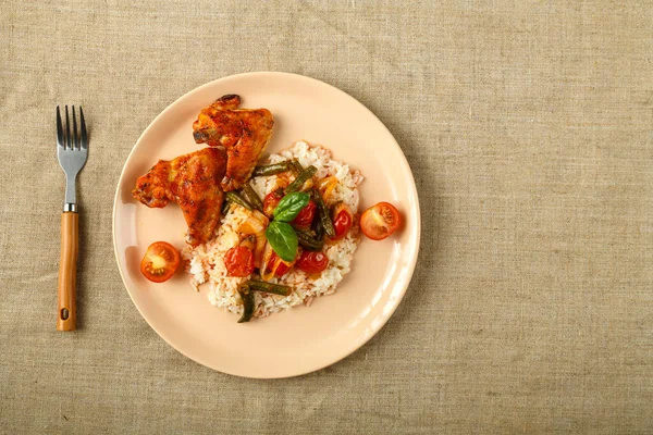 Domates soslu fırında tavuk kanadı pilav ve sebzeler keten masa örtüsünün üzerinde..